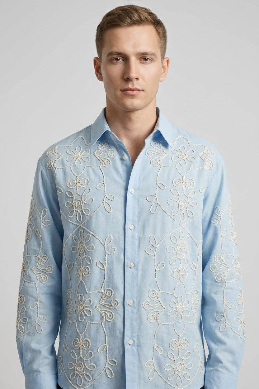 Modelo con camisa azul de manga larga y bordado floral en hilo hueso, vista frontal de estudio