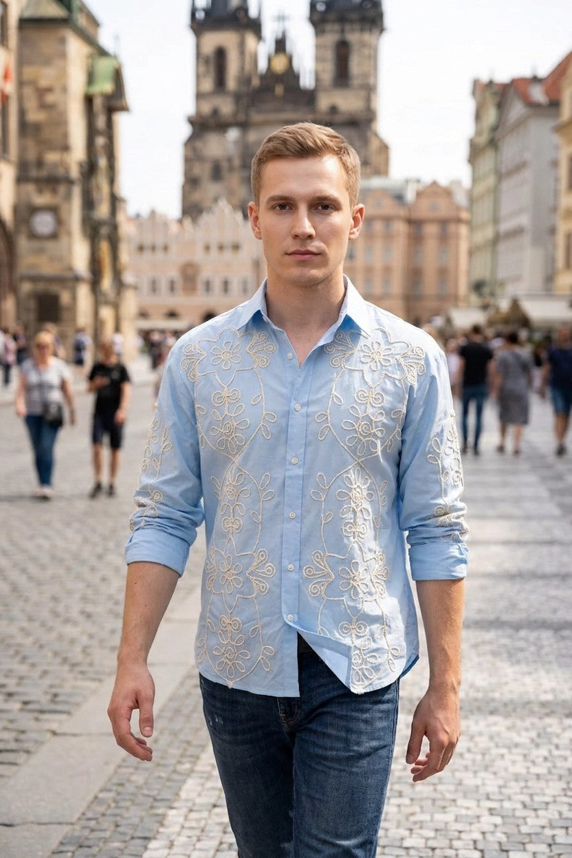 Modelo con camisa azul bordada combinada con vaqueros oscuros, look urbano en exteriores