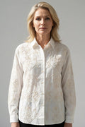 Modelo con camisa blanco de manga larga y bordado floral en hilo hueso, vista frontal de estudio