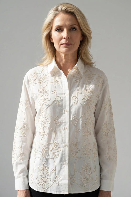 Modelo con camisa blanco de manga larga y bordado floral en hilo hueso, vista frontal de estudio