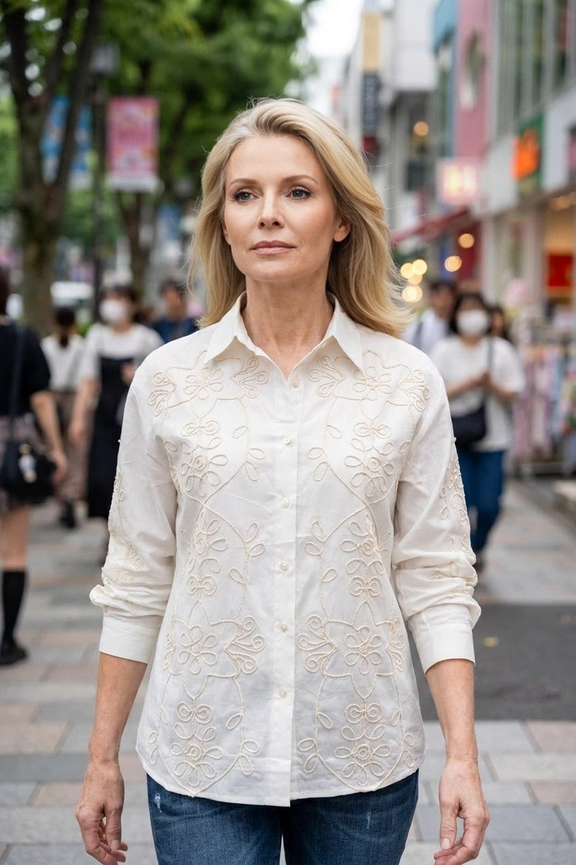 Modelo con camisa blanco bordada combinada con vaqueros oscuros, look urbano en exteriores