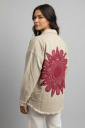 Espalda de chaqueta beige con gran bordado floral fucsia, modelo de espaldas