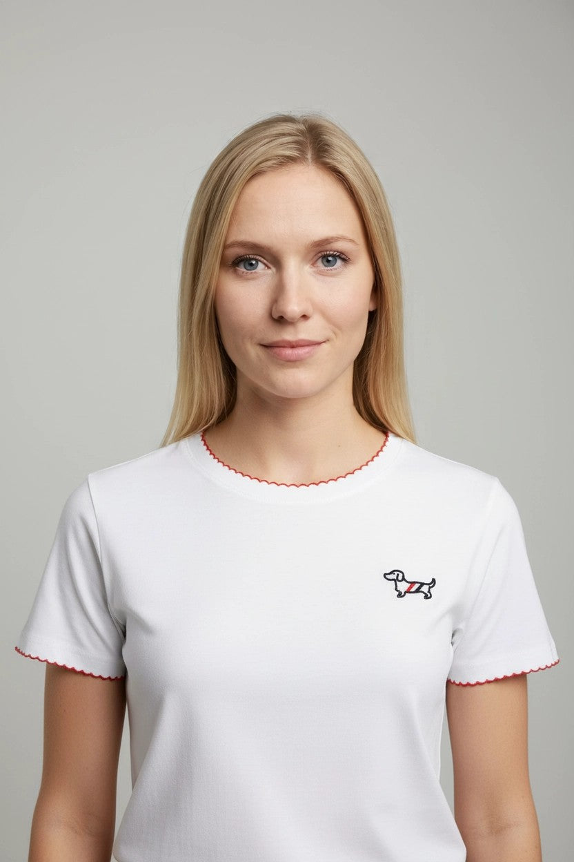 Camiseta blanca con ribete rojo y teckel bordado en pecho, vista frontal de estudio