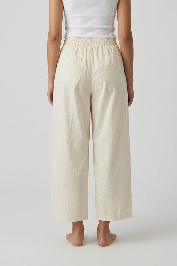 Vista trasera de pantalón baggy beige con cintura elástica, barefoot, tank top blanco