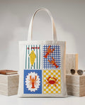 Tote bag blanca con ilustracion marina en cuatro cuadrantes: pez, langosta y cangrejo en colores vibrantes, vista frontal