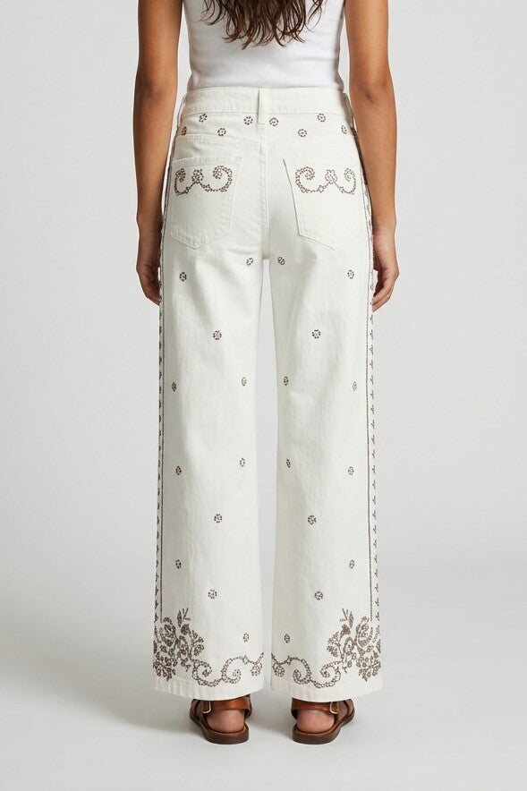 Vista trasera de pantalón vaquero blanco con bordados en bolsillos y cenefa floral en el bajo
