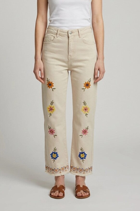 Mujer con pantalón beige de flores bordadas, vista frontal de estudio, combinado con camiseta blanca y sandalias