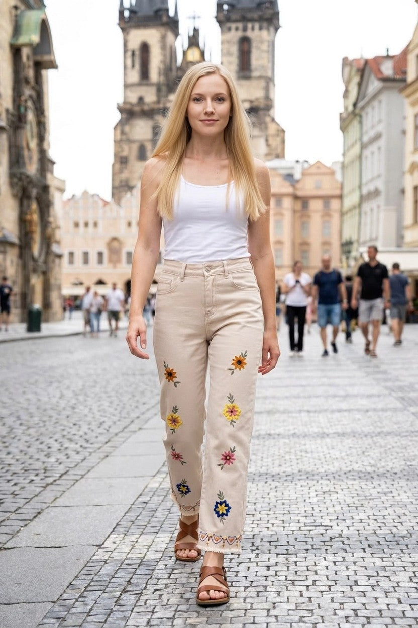 Modelo caminando en exterior urbano con pantalón beige de flores bordadas y camiseta blanca
