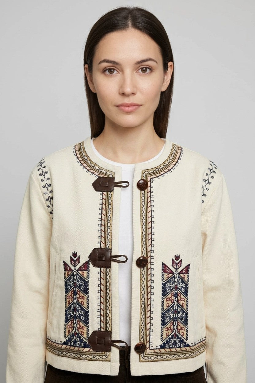 Mujer con chaqueta beige de bordados étnicos y cierres marrones, vista frontal de estudio