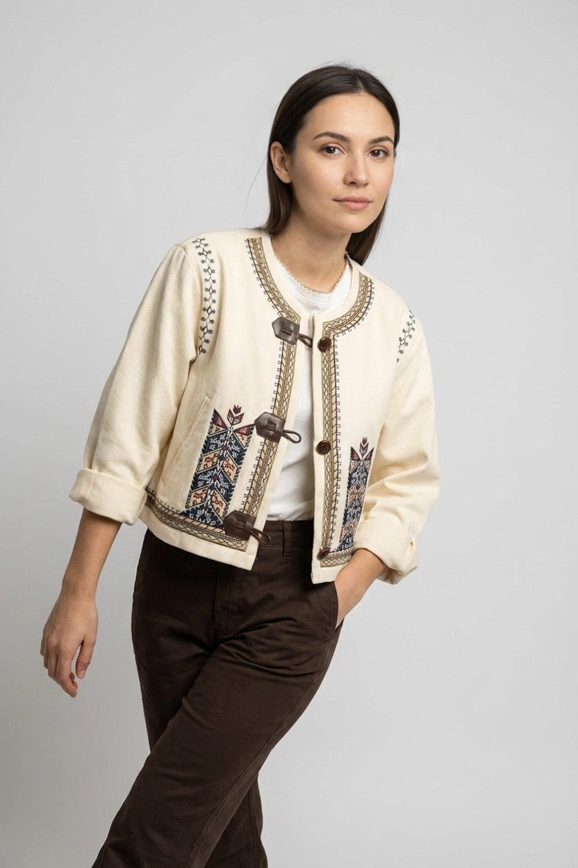 Mujer con chaqueta étnica beige y pantalón marrón, look de conjunto en estudio
