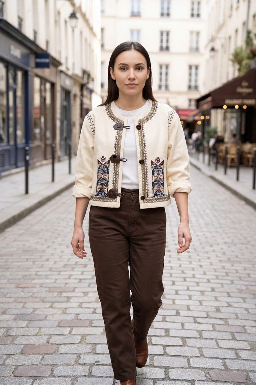 Modelo con chaqueta étnica beige paseando por calle empedrada, look de calle natural