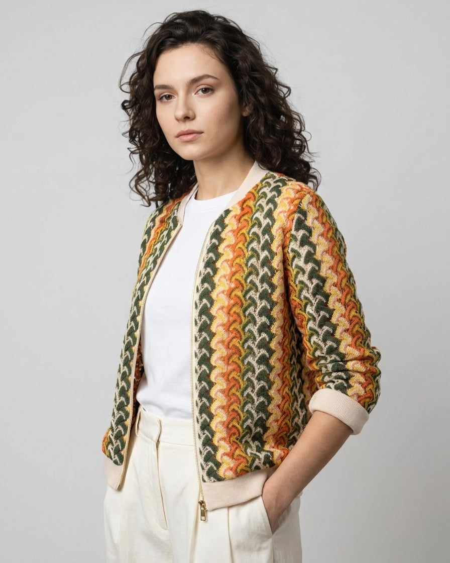 Detalle lateral de chaqueta bomber de punto jacquard tricolor con cremallera dorada, tres cuartos de estudio