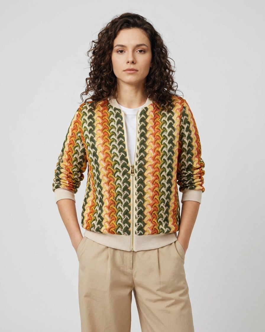 Mujer con chaqueta bomber de punto jacquard tricolor y pantalón beige, vista frontal completa de estudio