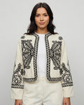 Mujer con chaqueta torera beige bordada en negro, vista frontal de estudio