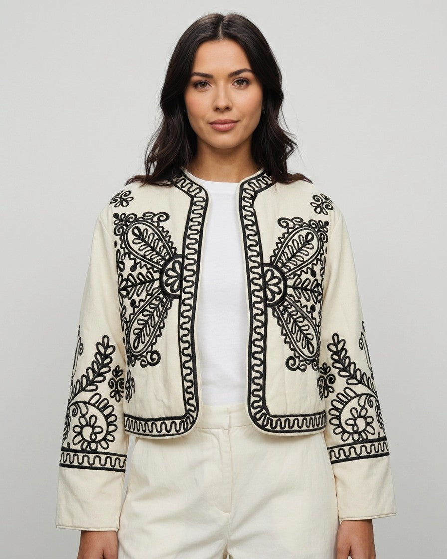 Mujer con chaqueta torera beige bordada en negro, vista frontal de estudio