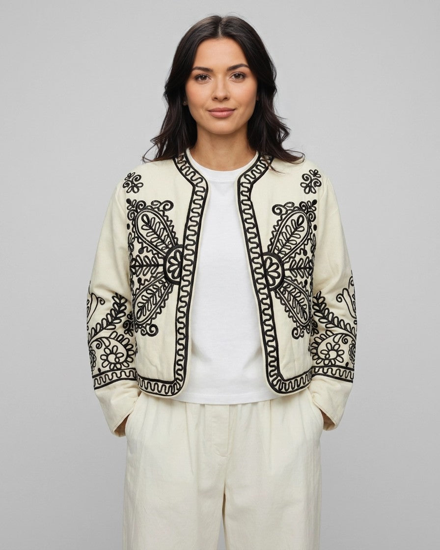 Mujer con chaqueta torera beige bordada, vista frontal con pantalón claro en estudio