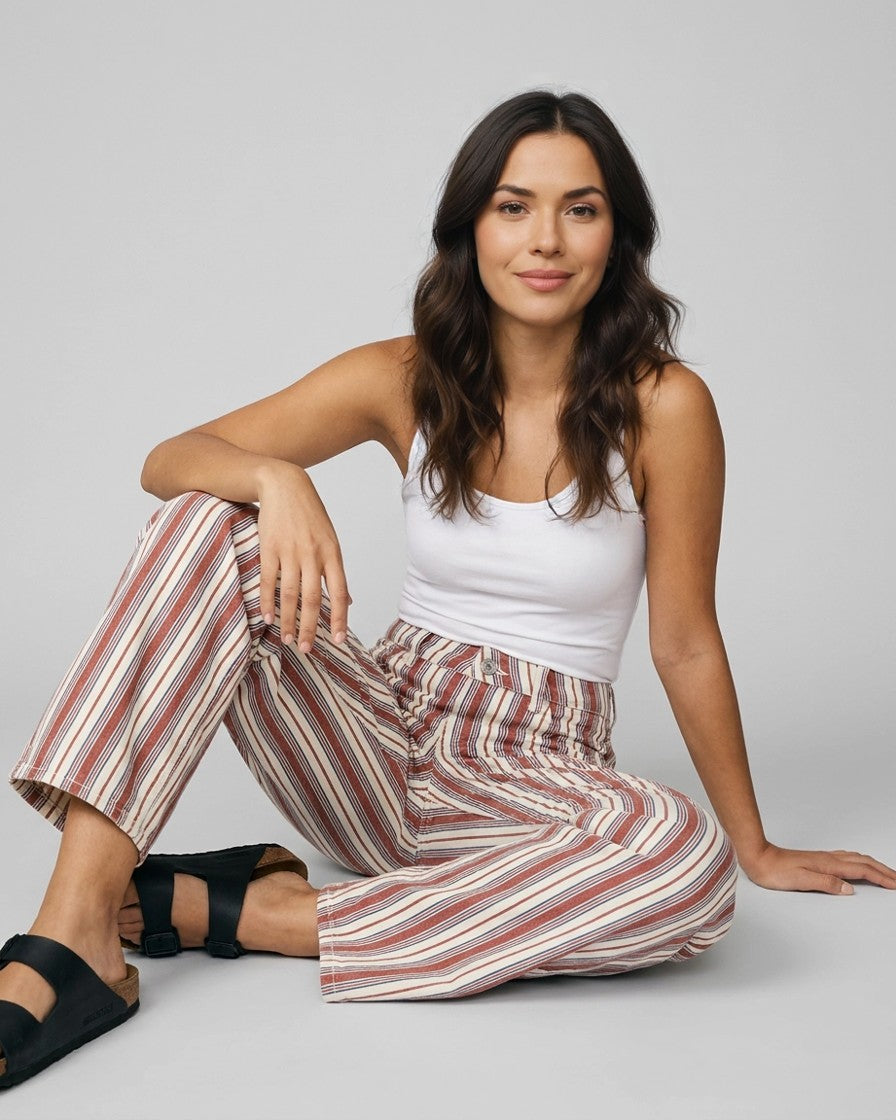 Modelo con pantalón baggy de rayas marrón y azul, pose casual sentada
